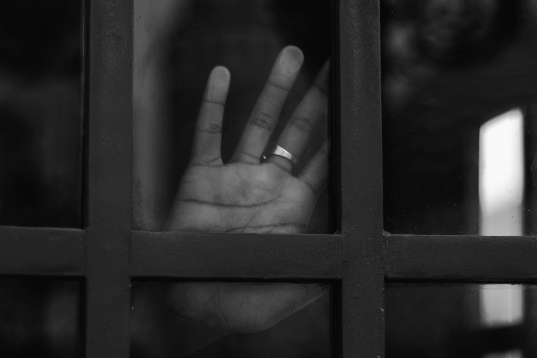 grayscale photo of persons hand on window