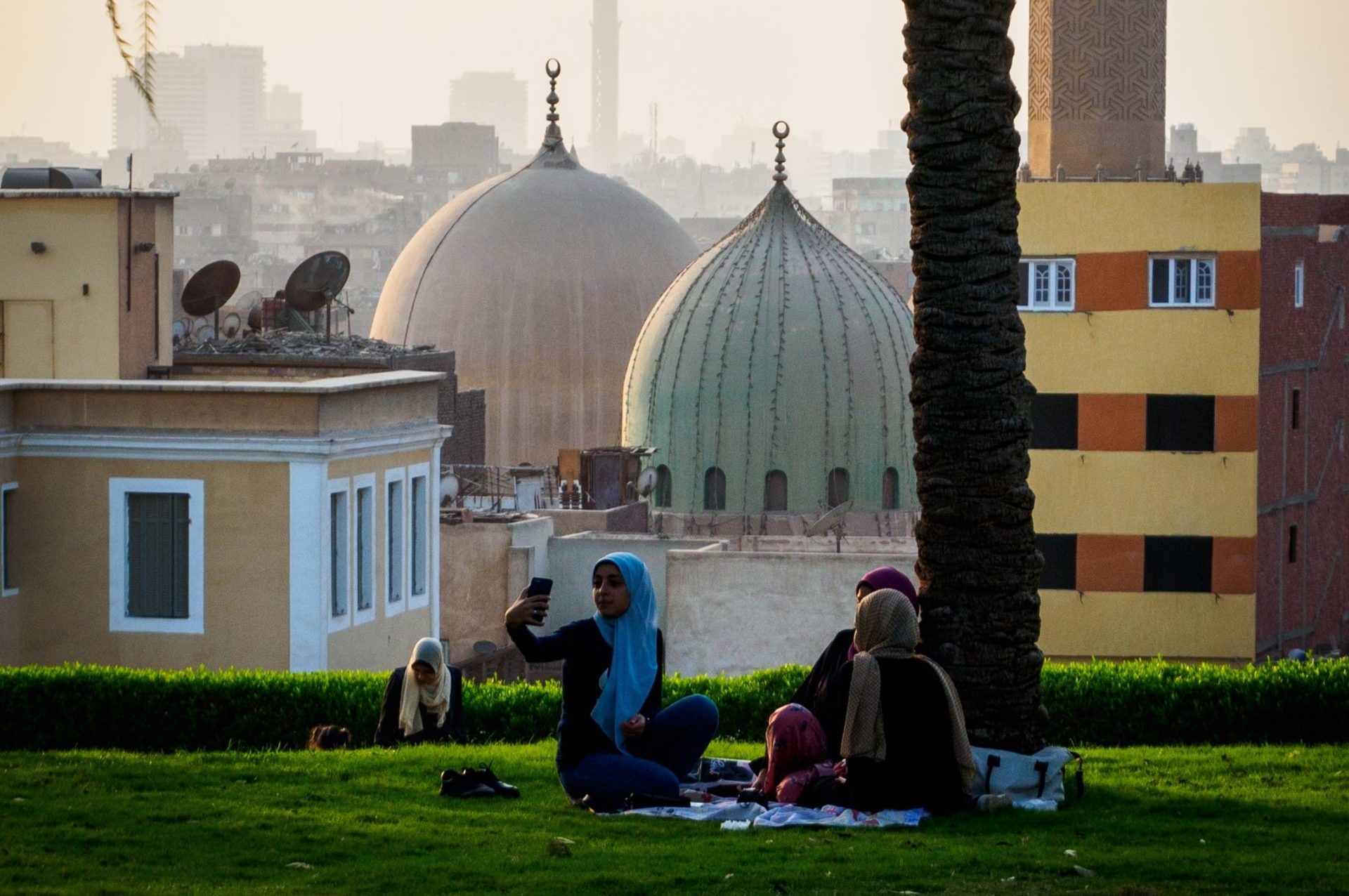 people sitting on grass near mosque